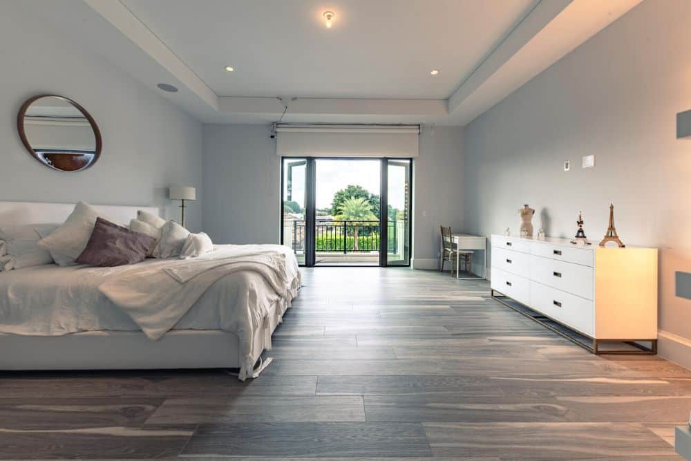This other bedroom has a large white bed across from the white dresser. On the far side is the balcony doors leading to the balcony.