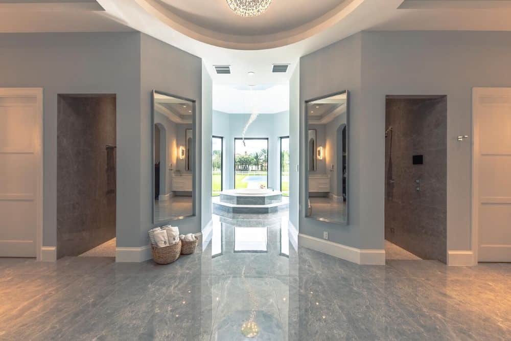 This is a full view of the primary bathroom showcasing the two shower areas on either side of the entryway leading to the bathtub on the far side by the windows.