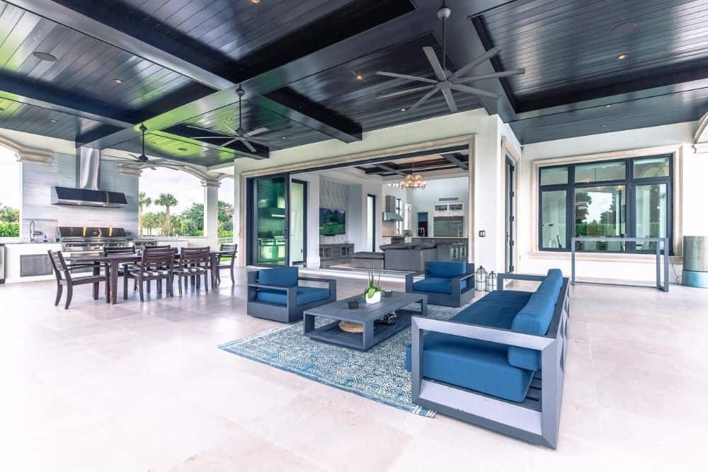 This is a close look at the large covered patio area with an outdoor living room, outdoor dining area and an outdoor kitchen on the far side.