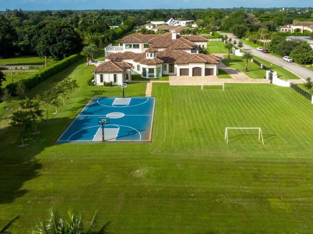 This is an aerial view of the property showcasing the large basketball court and large football field beside it.