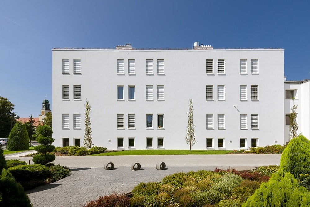 This view of the side of the monastery showcases the landscaping of walkways and miniature gardens that pair well with the netral beige exteriors of the monastery.