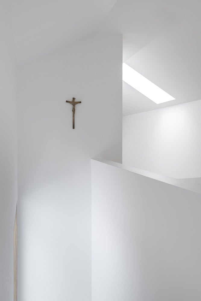 This is a close look at one of the brilliant white walls of the monastery interiors with a modern style complemented by the wall-mounted crucifix.