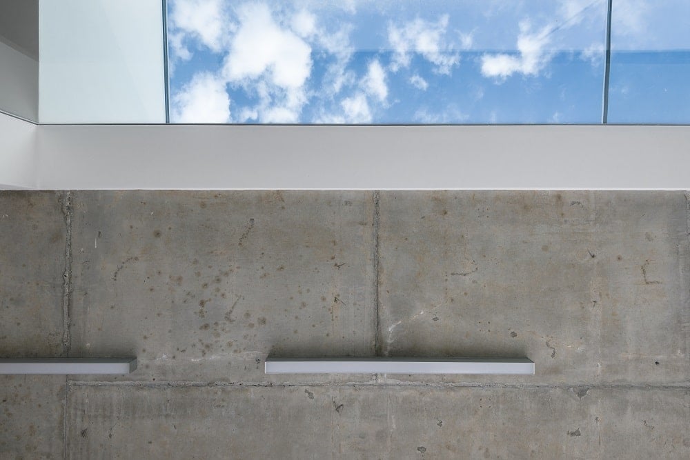 This is a look at the concrete ceiling of the walkway that has fluorescent lights and a a large skylight.