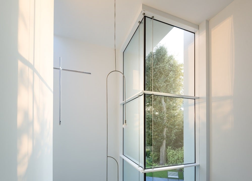 This is a close look at the tall glass wall and white wall with crucifix of the lobby atrium.