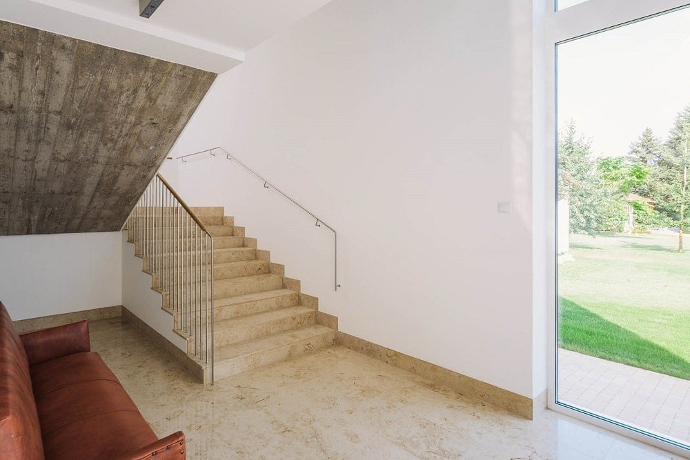 This is a look at the interior staircase with railings on the side leading to a glass door to access the exterior.