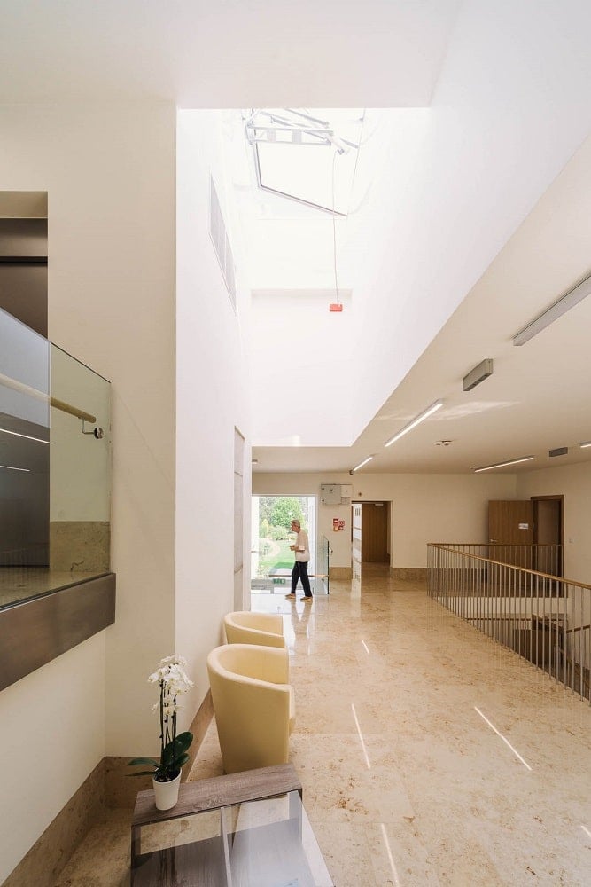 This is a look at the upper level landing and indoor balcony bordered with railings an topped with a bright beige ceiling.
