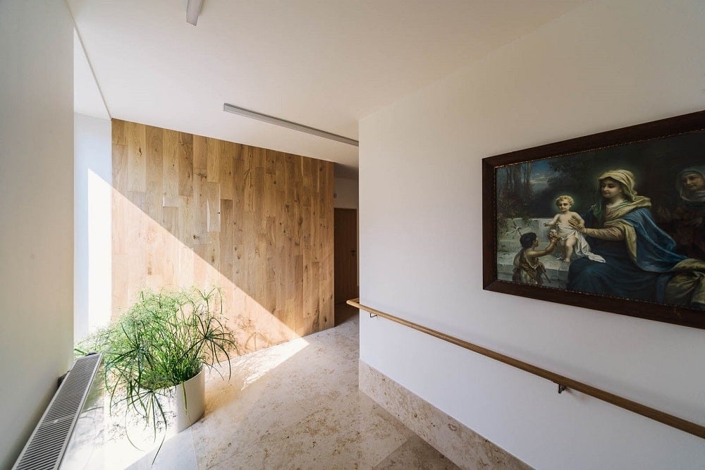 This is a closer look at the end of the hallway with a potted plant at the corner and a wall-mounted artwork on the side.
