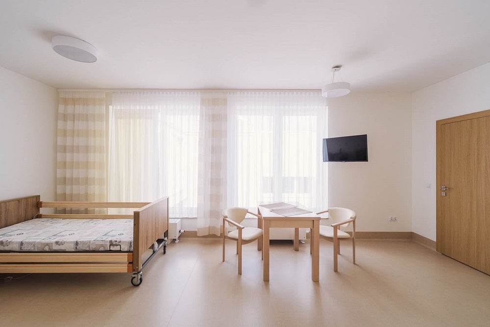 This is a view of one of the room with a large wooden bed with wheels and a small dining area on the side.