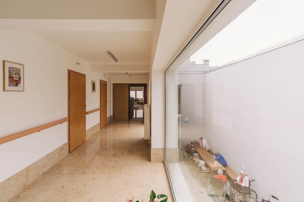 Outside the glass wall of the hallway is a view of the courtyard below with an out dining area.