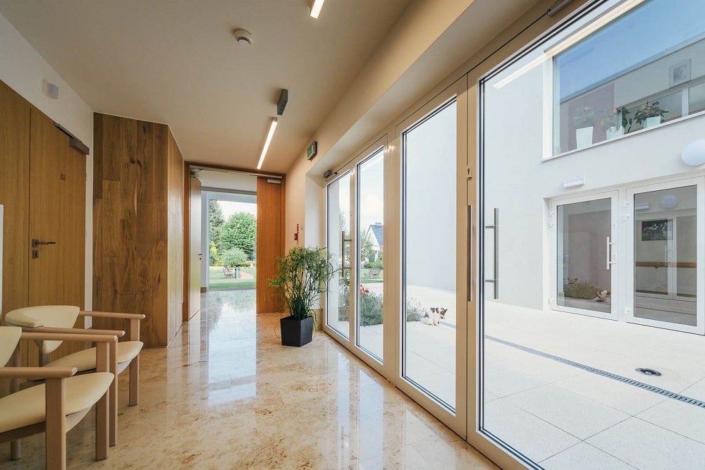 This is a side of the interior of the senior house with a set of glass doors adorned with a potted plant on the side.