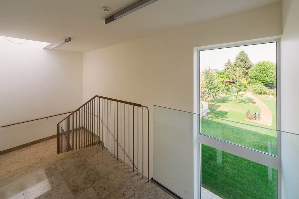 This is the upper level landing and indoor balcony with railings and a view of the large glass wall.