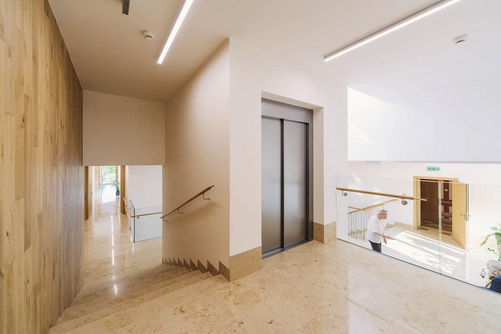 The interior also has its own elevator with stainless steel doors on the side of the staircase.