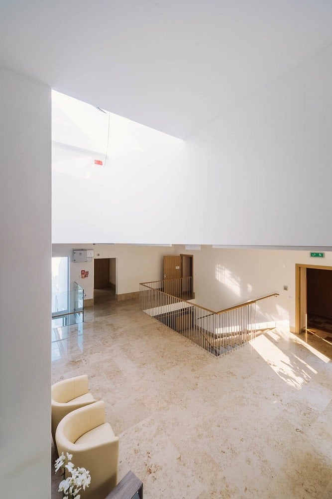 The senior house has large hallways with beige floors and tall ceiling brightly lit with natural lighting.