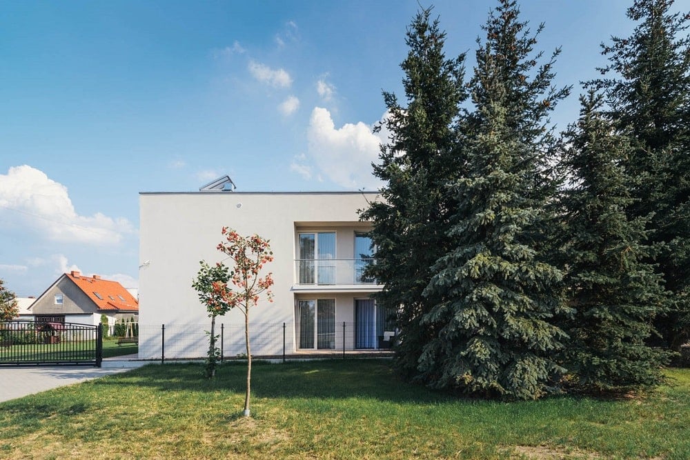 This is a look at the exteriors with beige exterior walls and windows adorned by the lush landscaping of tall trees and grass lawns.