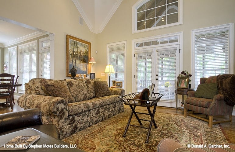 The living room offers a floral sofa, striped armchairs, and a wooden coffee table that sits on a classic area rug.