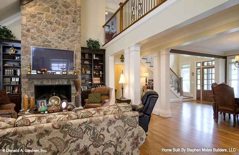 The living room includes a stone fireplace nestled between the wooden built-ins.