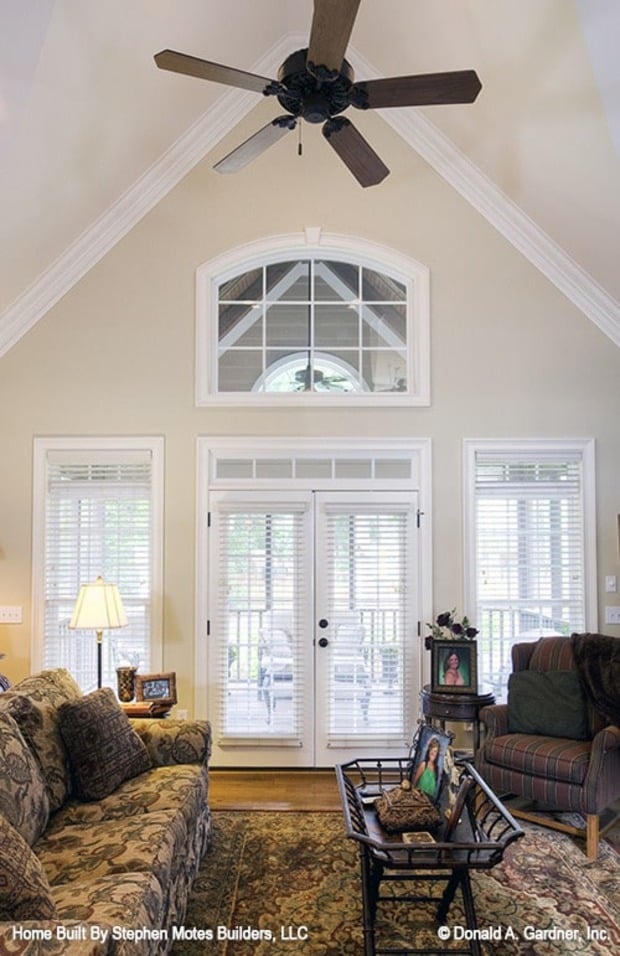 A cathedral ceiling mounted with a ceiling fan tops the living room.