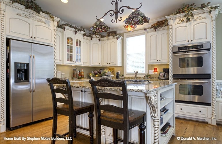 The kitchen offers white cabinetry, stainless steel appliances, granite countertops, and a breakfast island.