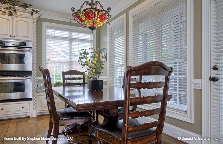 Breakfast nook with a dark wood dining set well-lit by a lovely stained glass pendant.