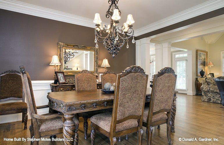 Formal dining room with an ornate wrought iron chandelier, a classic rectangular dining set, and a matching buffet table paired with a framed mirror.