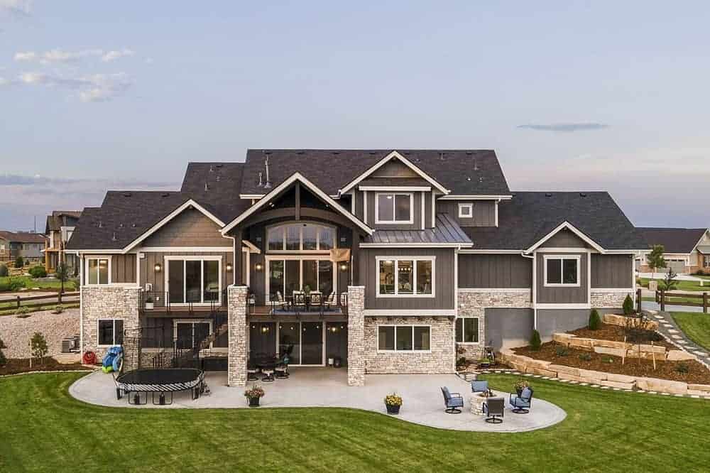 This is an aerial view of the back of the house that has a fire pit area and a trampoline area by the grass lawn and a large planter on the side of the house with terraces.