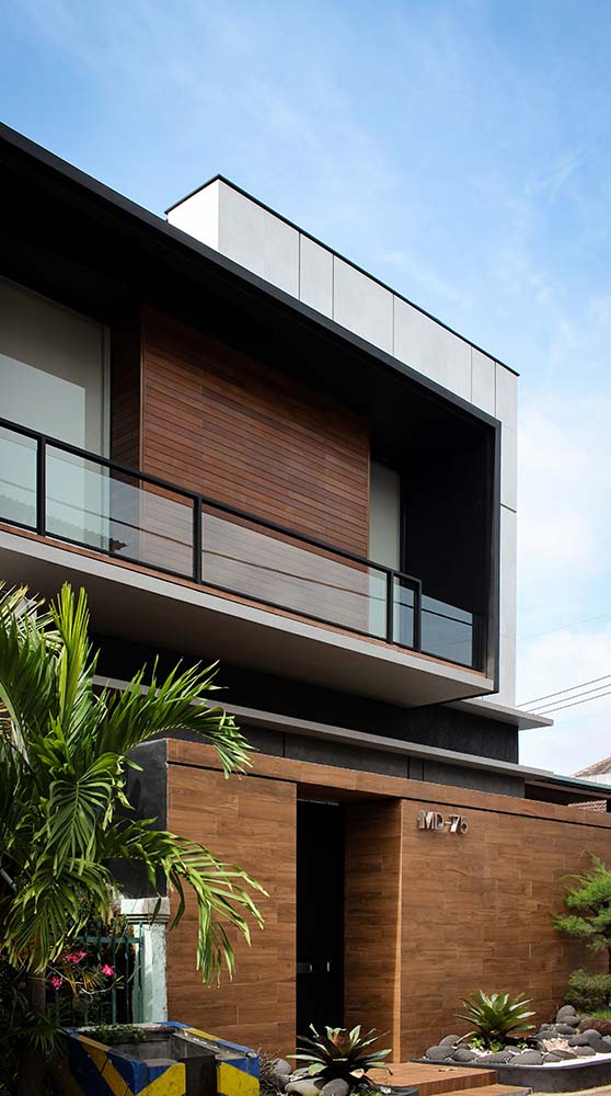 This is a close look at the front of the house that has various tones and materials on its façade adorned by the medium-sized trees and shrubs.