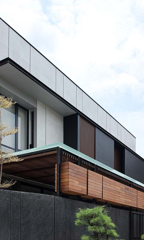 This is a close look at the upper level of the house that has bright elements that contrast the dark wooden panels as well as the dark glass walls.