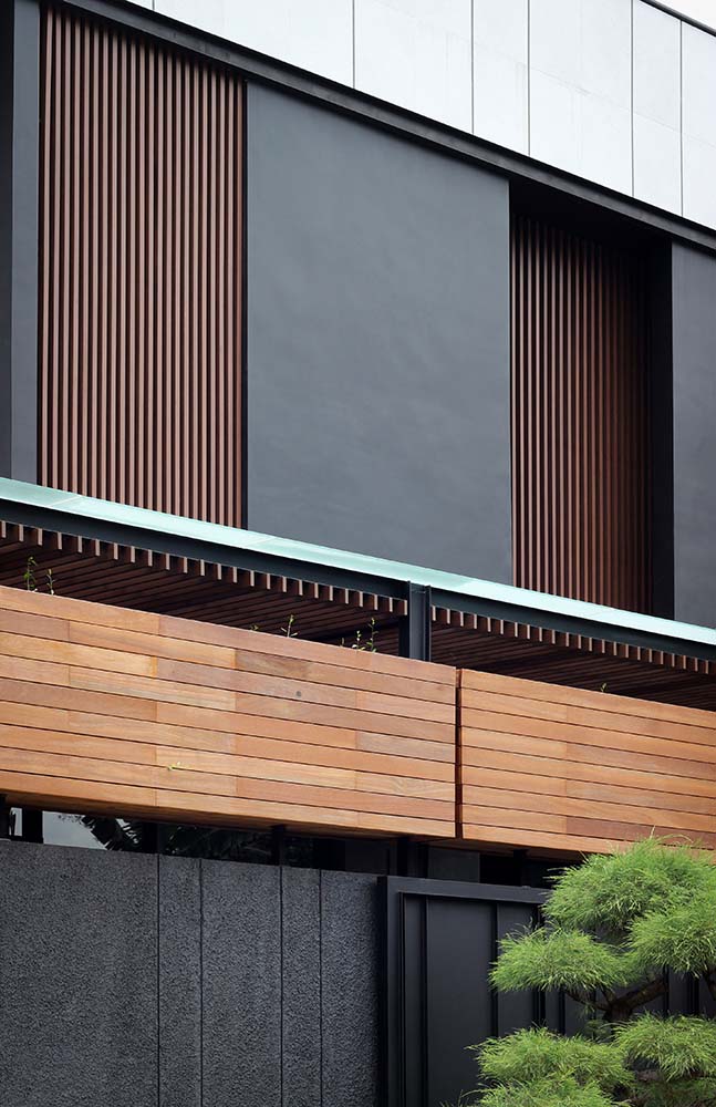This is a close look at the upper level of the house with dark wooden slatted panels paired with dark gray charcoal panels.