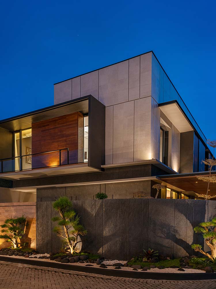 This view of the house exterior also showcases the balconies of the upper level with their own lighting that matches the landscaping and interior lights.