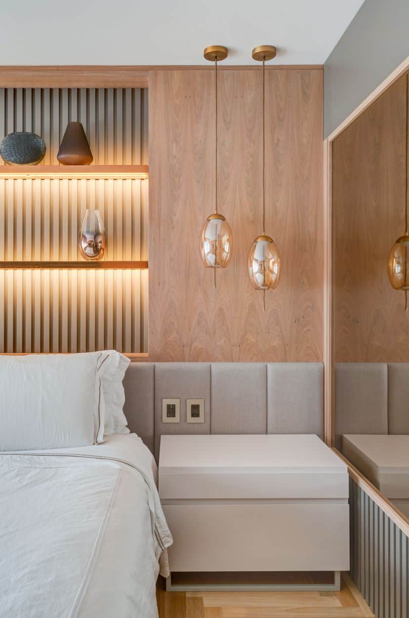 This is a close look at the bedroom with a bed that has a cushioned headboard that extends to the bedside table topped with a couple of pendant lights.