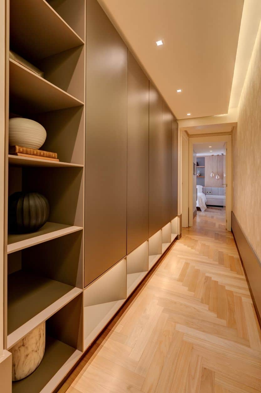 This is the hallway that leads from the living room area with a set of cabinets and shelves on the side adorned by the beige wall and ceiling.