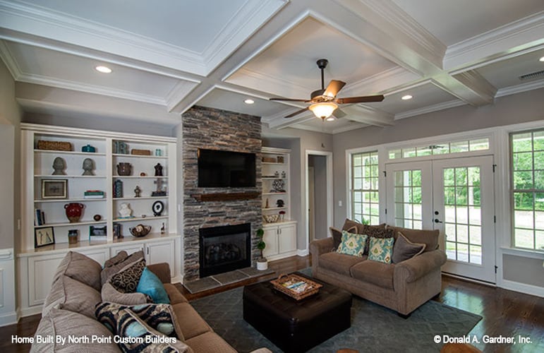 The living room offers brown sofas, a leather ottoman, and a fireplace topped with a TV.