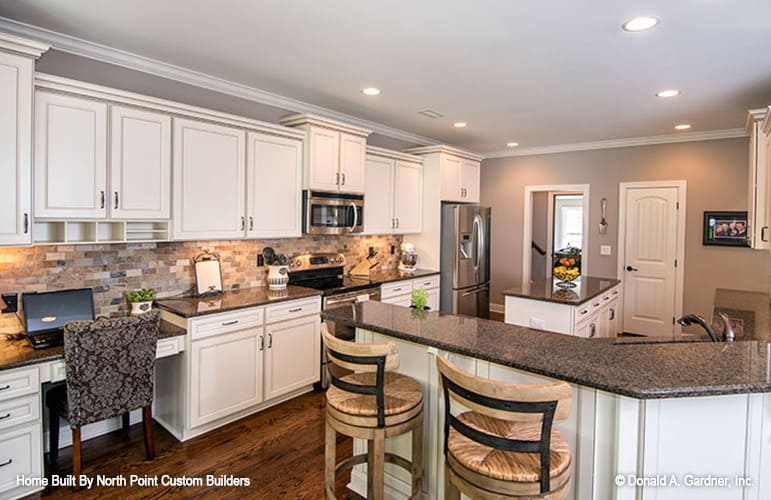 The kitchen includes a built-in desk paired with a patterned chair.