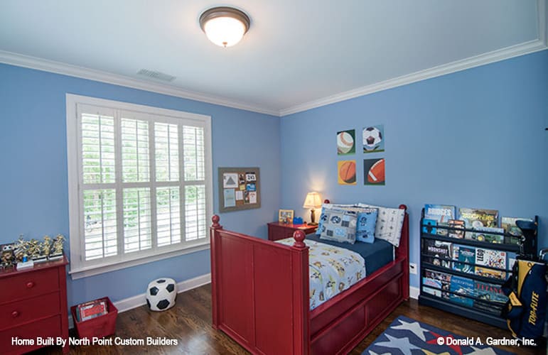 Kid's bedroom with blue walls, redwood furnishings, and dark hardwood flooring.