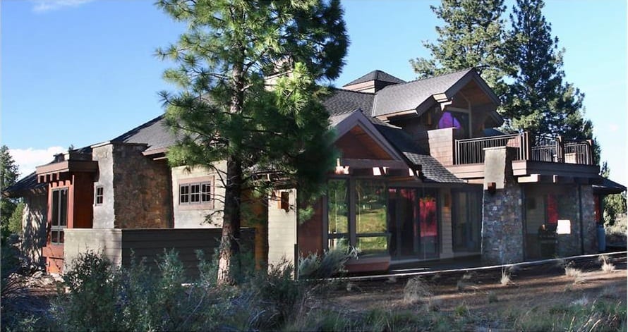 Rear exterior view with an expansive porch and a sun deck supported by large stone columns.