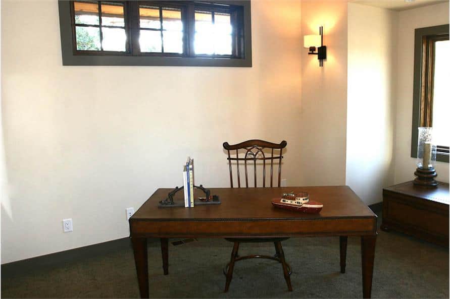 Study with a wooden desk and chair over carpet flooring.
