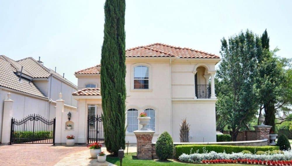 Front exterior view showing the stucco siding, clay tile roofs, and wrought iron gate.