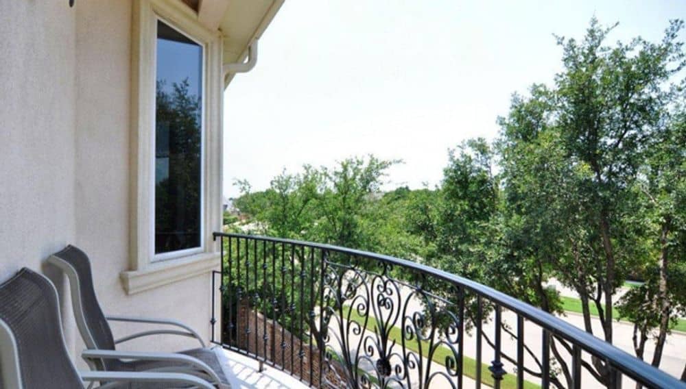 Balcony with gray loungers and a wrought iron railing.