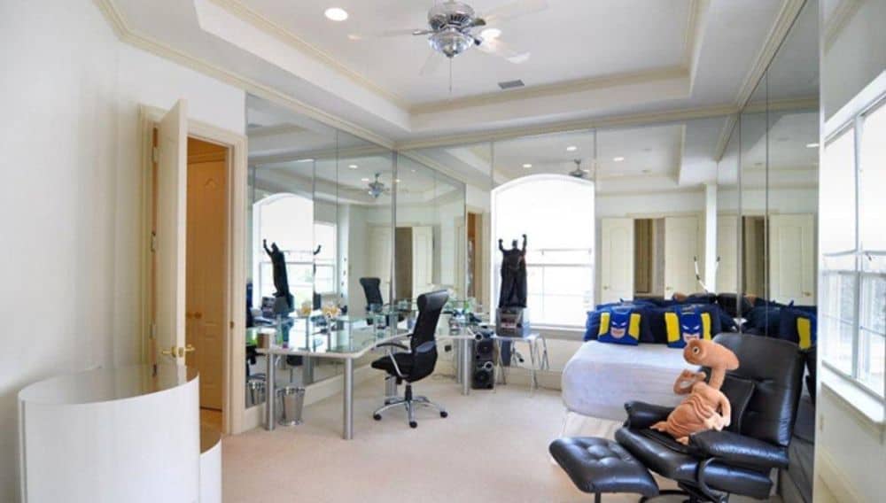 This bedroom features mirrored walls, carpet flooring, and a tray ceiling.
