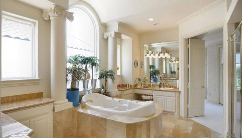 Primary bathroom with his and her vanities, a walk-in shower, and a deep soaking tub flanked by interior columns.
