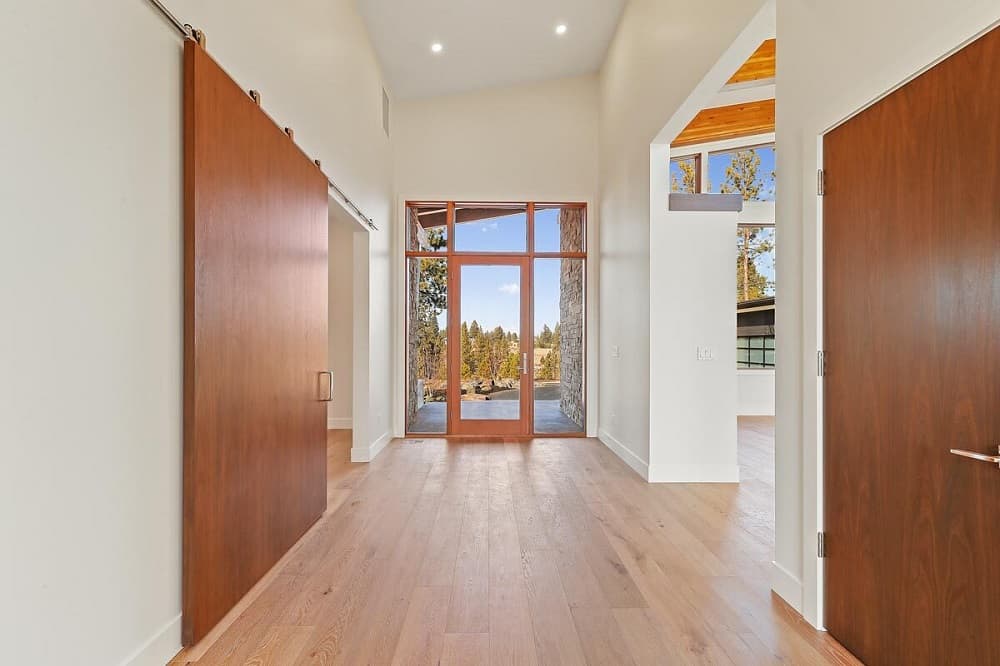 Upon entry into the home, you are welcomed by this simple foyer with a glass door surrounded by glass panels that brighten the beige walls and tall beige ceiling.