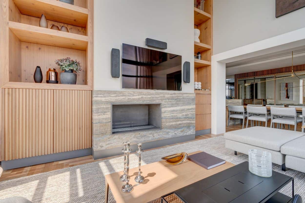 Across from the L-shaped sectional sofa is the modern fireplace flanked by built-in cabinets and topped with a wall-mounted TV.