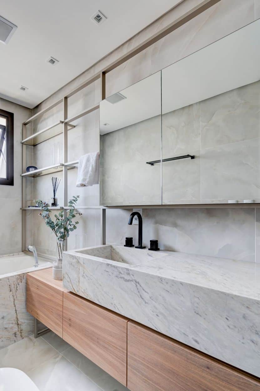 This is a close look at the bathroom that has a large white marble structure on its sink vanity area matching with the bathtub housing.