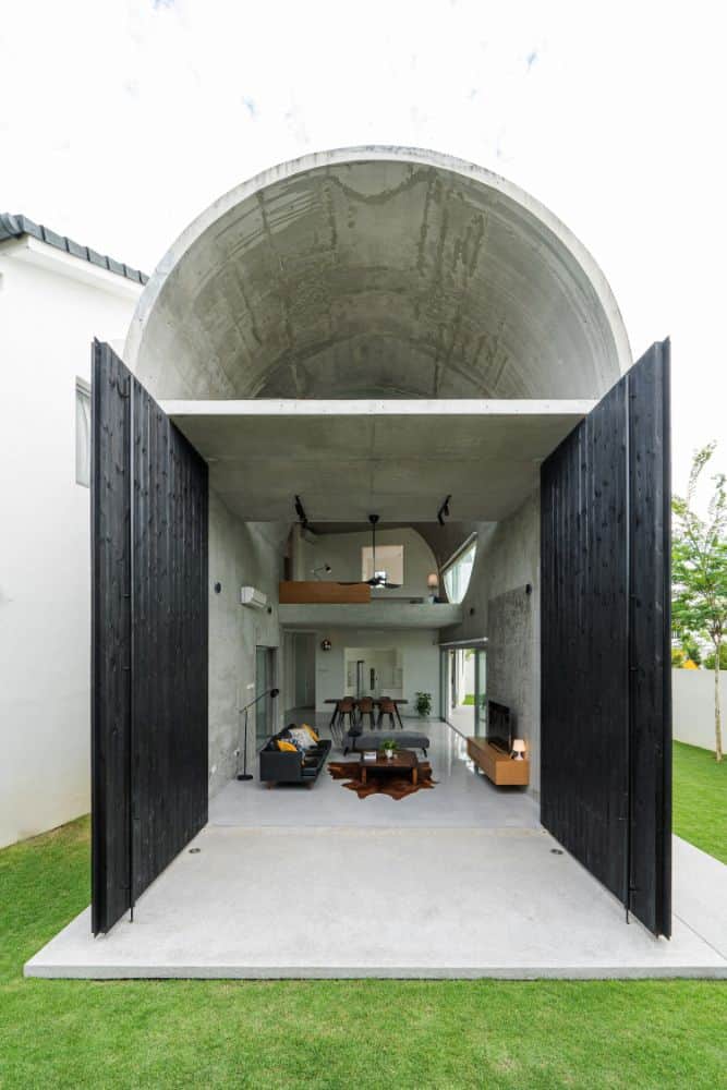 The wooden shiplap wall of the arched structure opens up to reveal the interior of the house.