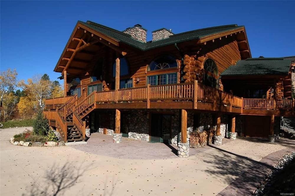 This is the front of the house that has consistent dark wooden structures and exterior walls complemented by the landscape of concrete walkway, miniature gardens with small pines and graveled soil.