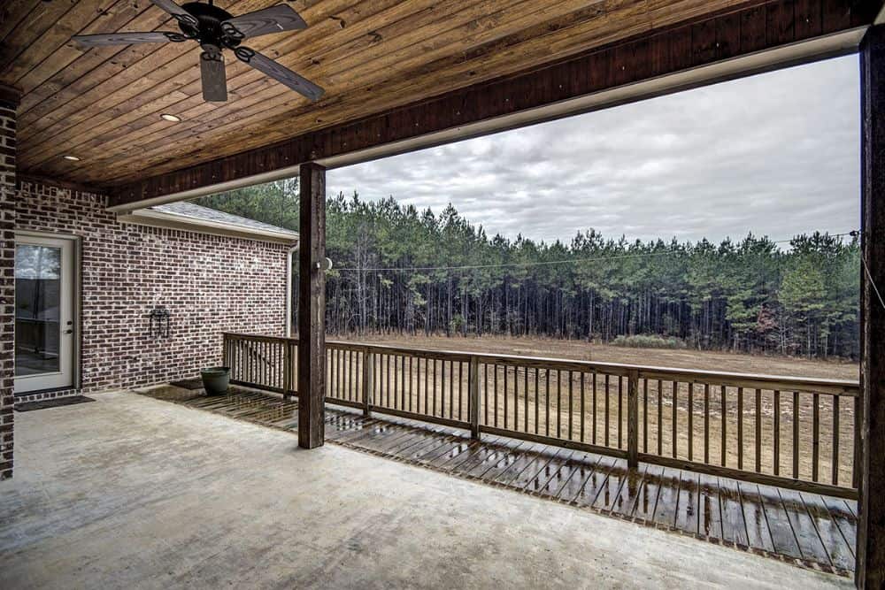 The covered porch overlooks the expansive yard and the forest beyond.