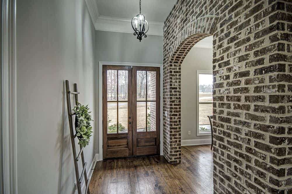 Foyer with a wooden ladder and a brick archway leading to the formal dining room.