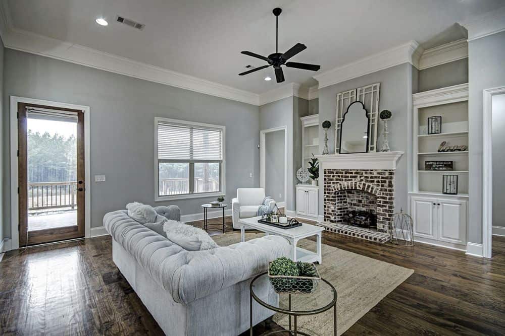 Living room with a chesterfield sofa, white armchair, a matching coffee table, and a brick fireplace.
