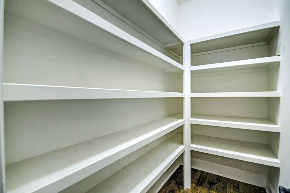 The walk-in pantry is filled with white built-in shelves.