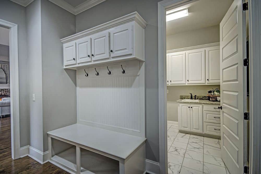 Mudroom with built-in storage and bench. A white door on its side opens to the utility room.
